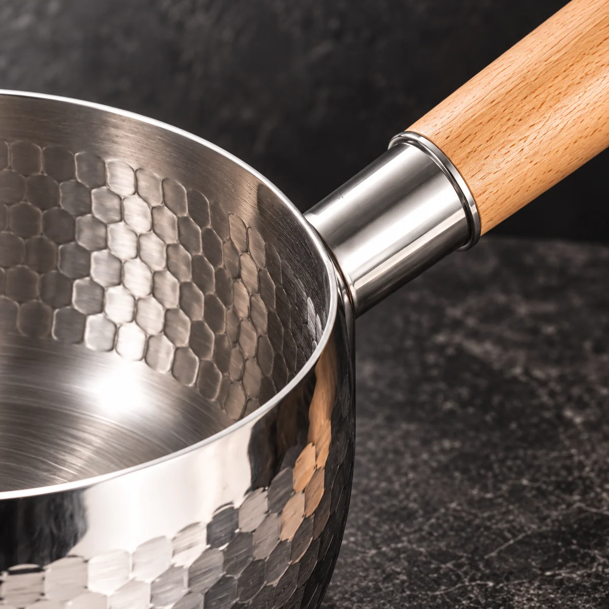 Close-up of the wooden saucepan handle and hammered metal